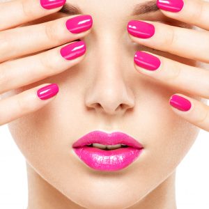 Close-up face of a beautiful  girl with bright pink  nails and lips.