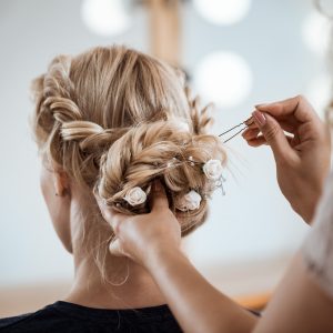 Female hairdresser making hairstyle to beautiful blonde girl in beauty salon. Copy space.